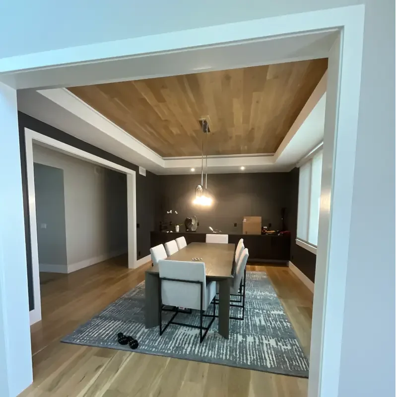 Luxury dining room interior painting project featuring dramatic dark accent walls, custom tray ceiling with natural wood inlay, recessed lighting, and modern fine finish detailing. Professional interior painting and custom finish services for upscale