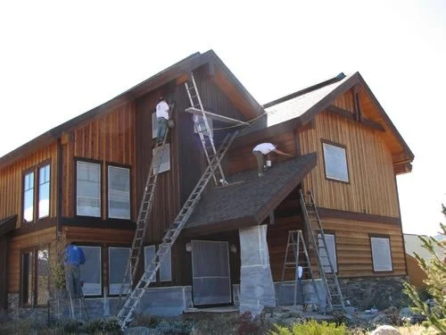 Exterior wood siding staining and painting project on a custom mountain home featuring cedar siding, timber accents, and multi-level architectural detailing. Professional exterior painting, wood staining, and custom home finishing services for luxury