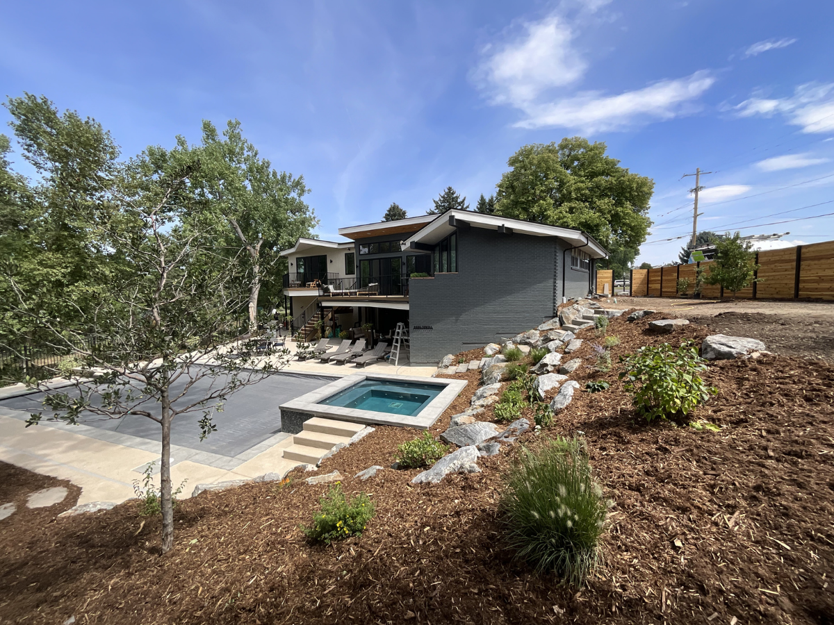 Contemporary residential exterior painting project featuring dark charcoal brick finishes, modern architectural lines, custom wood soffits, and luxury outdoor living spaces with pool and spa area. Professional exterior painting and staining services 