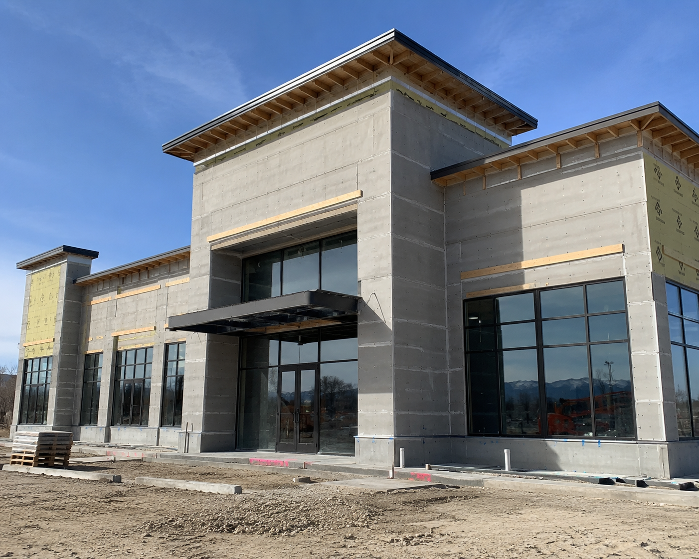 Commercial building under construction with exterior surfaces prepped for painting, featuring modern architectural design, unfinished siding, and large-scale new construction project in Colorado.