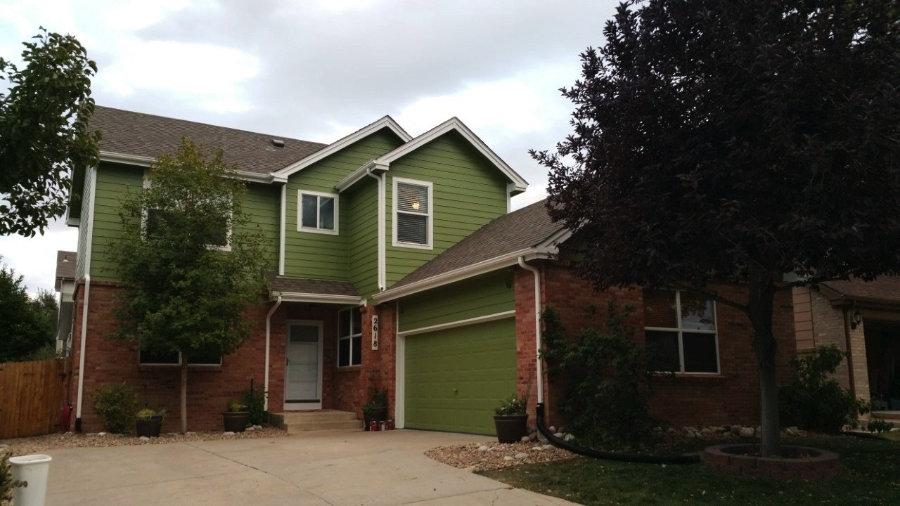 Residential exterior repainting project featuring updated green siding, white trim accents, and refreshed curb appeal for a two-story suburban home. Professional exterior painting and siding repaint services for residential homes, neighborhood proper