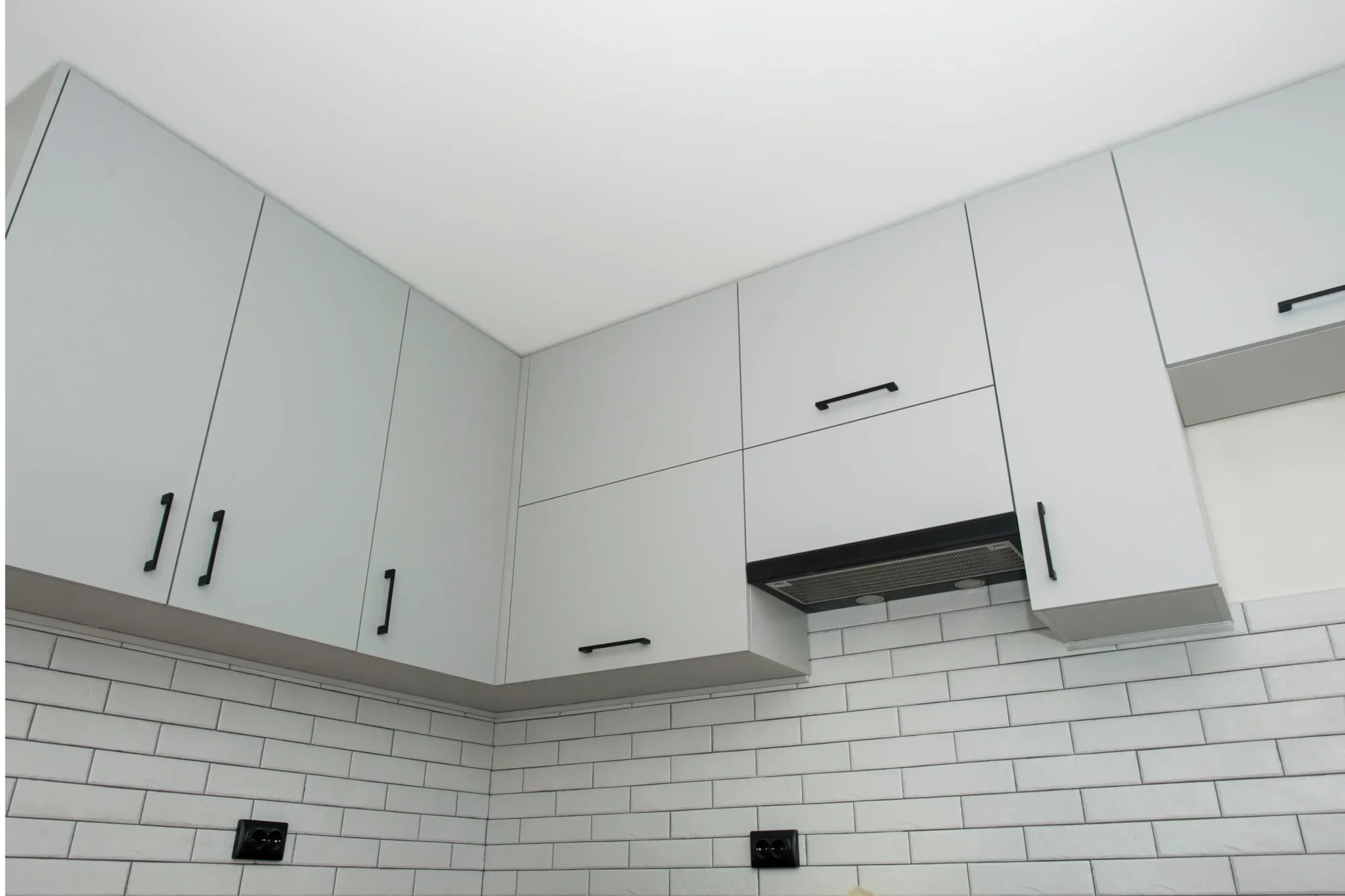 Cabinet painting project showing freshly finished kitchen cabinets with smooth white surfaces, clean lines, and updated modern hardware.