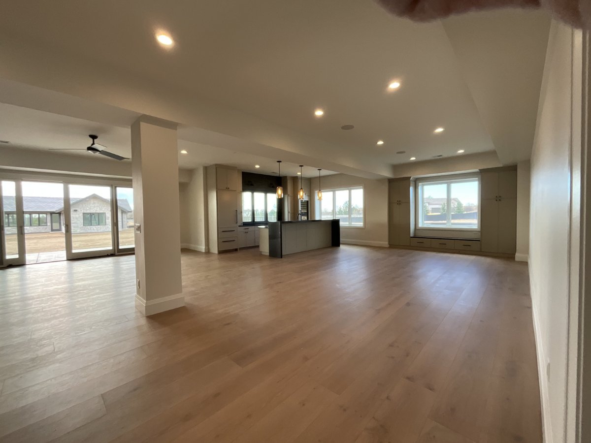 Modern open-concept interior painting project featuring custom cabinetry, recessed lighting, wide plank hardwood flooring, and clean contemporary finishes throughout a luxury residential living space. Professional interior painting and fine finish se