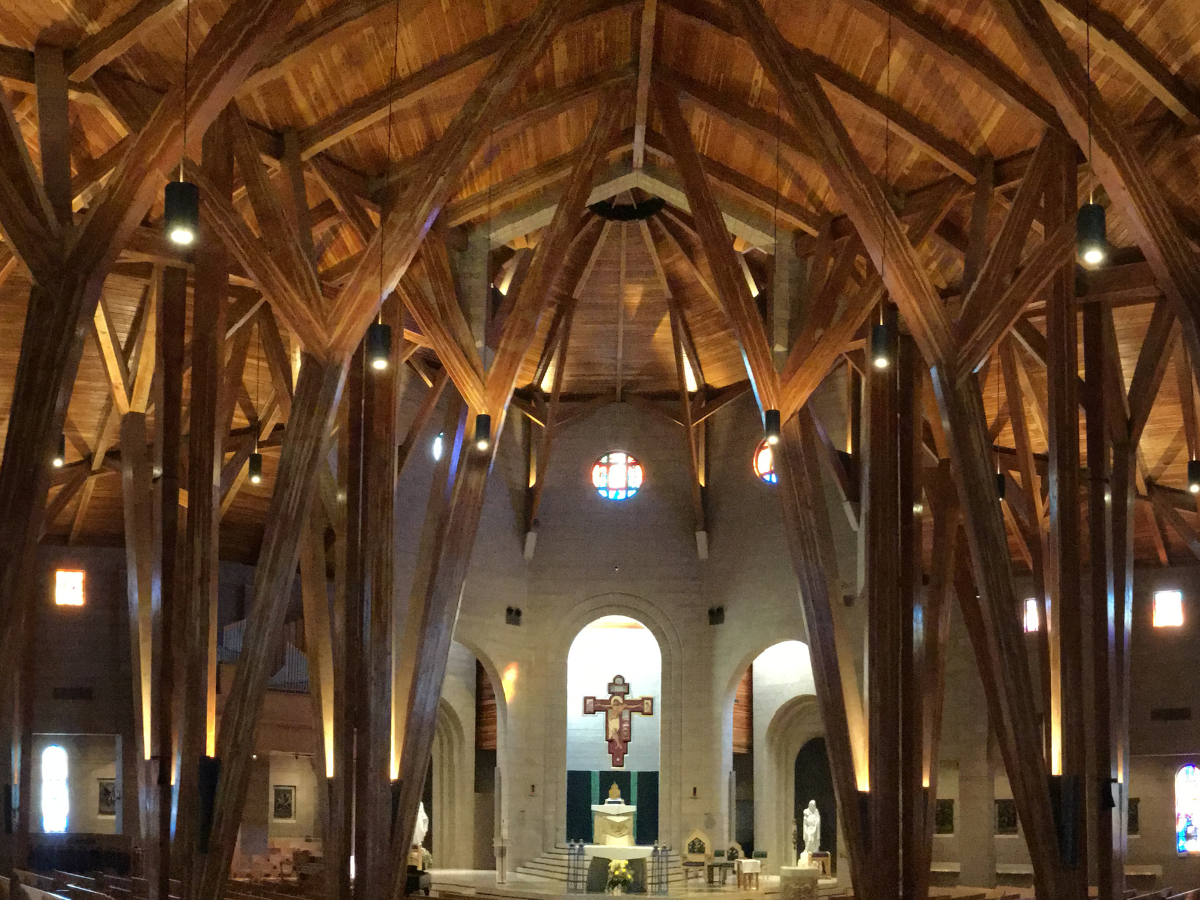Commercial interior wood finishing project featuring custom timber staining, vaulted architectural woodwork, and detailed finish craftsmanship inside large-scale worship and gathering space.