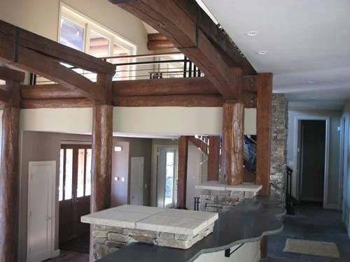 Rustic luxury home interior featuring exposed timber beams, natural wood finishes, stone accents, and professionally painted interior walls in custom Colorado mountain home.