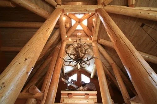 Luxury mountain home interior painting and wood finishing project featuring exposed log beams, vaulted timber ceilings, rustic architectural detailing, and custom lodge-style craftsmanship. Professional interior painting and fine finish services for 