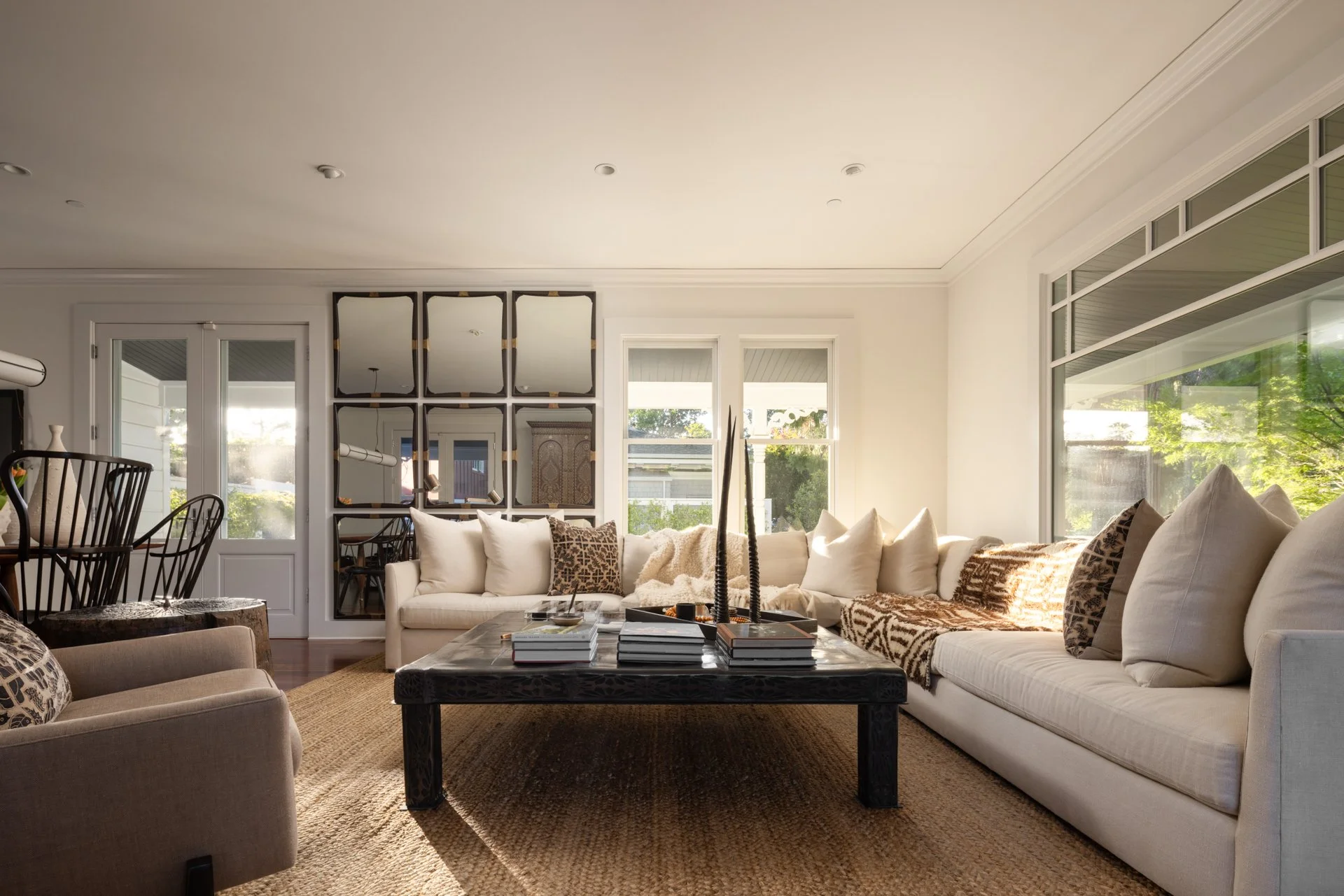 Living room with a white sofa, beige armchair, coffee table, and large window with greenery outside.