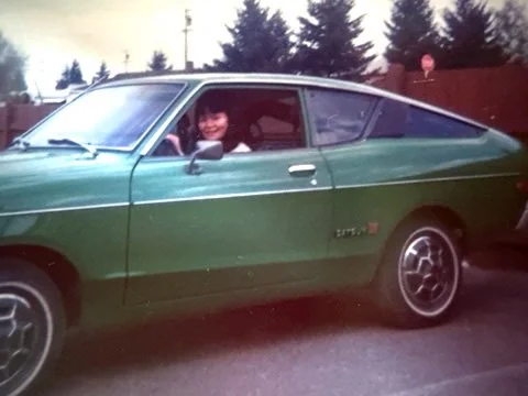 Woman smiling from inside green Datsun B210