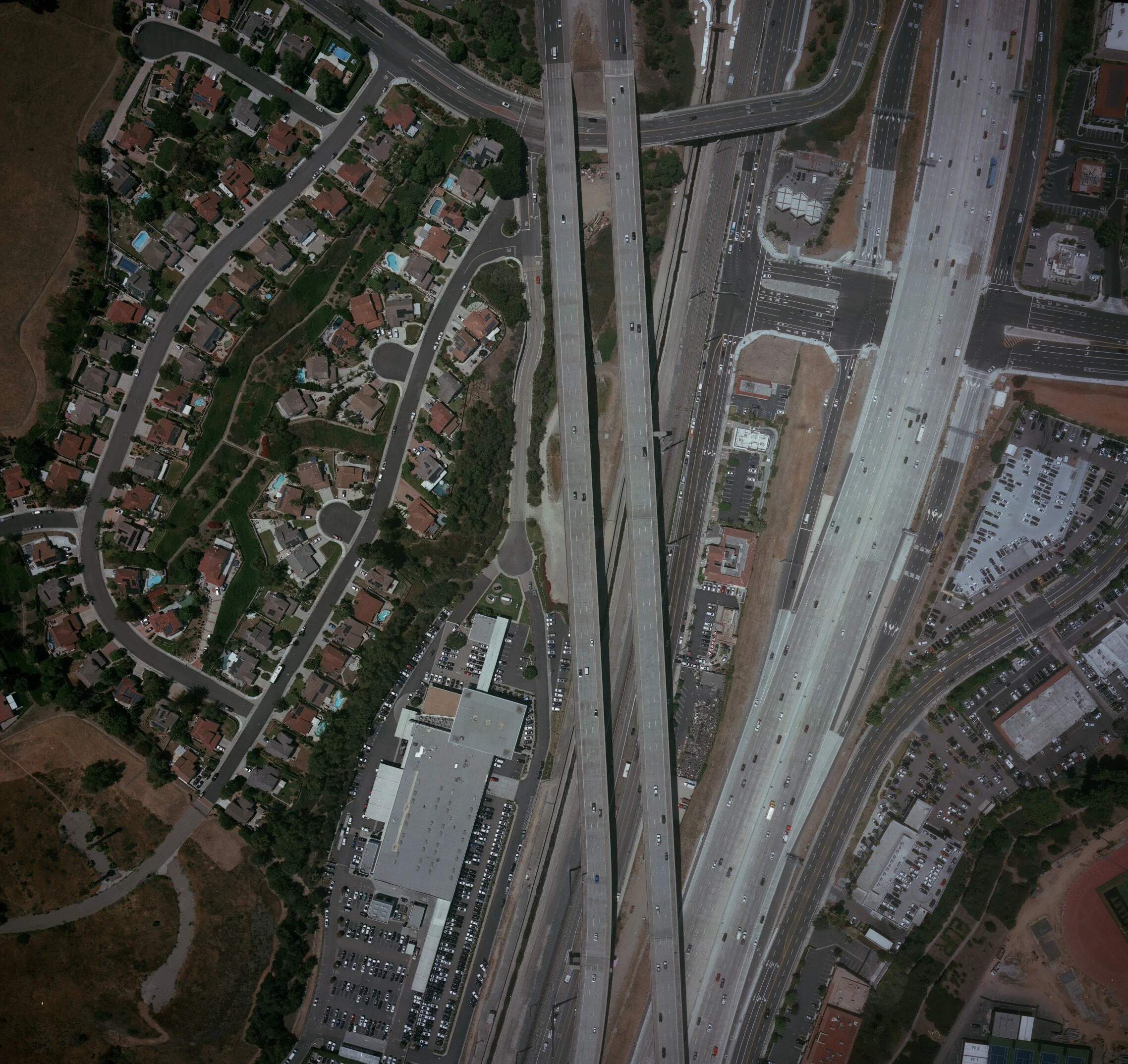 An aerial photo view of a city intersection showing multiple roads, houses with swimming pools, parking lots, and commercial buildings. Mapping, topographic maps, GIS, LiDAR, aerial mapping, SoCal, Southern California, aerial mapping, aerial imagery