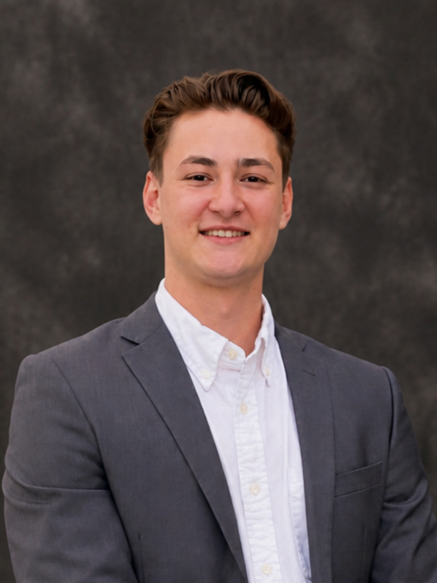 Blake Lung, a photogrammetrist at RJL & Associates, with brown hair, wearing a light gray suit and white dress shirt, smiling against a dark background.
