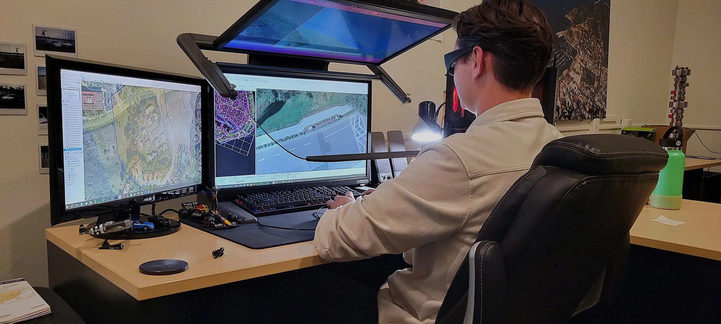 Person working at a PluraView 3D monitor computer setup with maps and design software (CAD), in an office with photos on the wall. Mapping, topographic maps, GIS, LiDAR, aerial mapping, SoCal, Southern California, aerial imagery