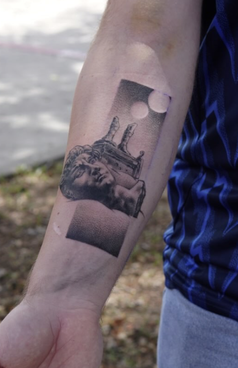 Black and gray tattoo of a modern design of a statue with a circle details in the background on a person's forearm.