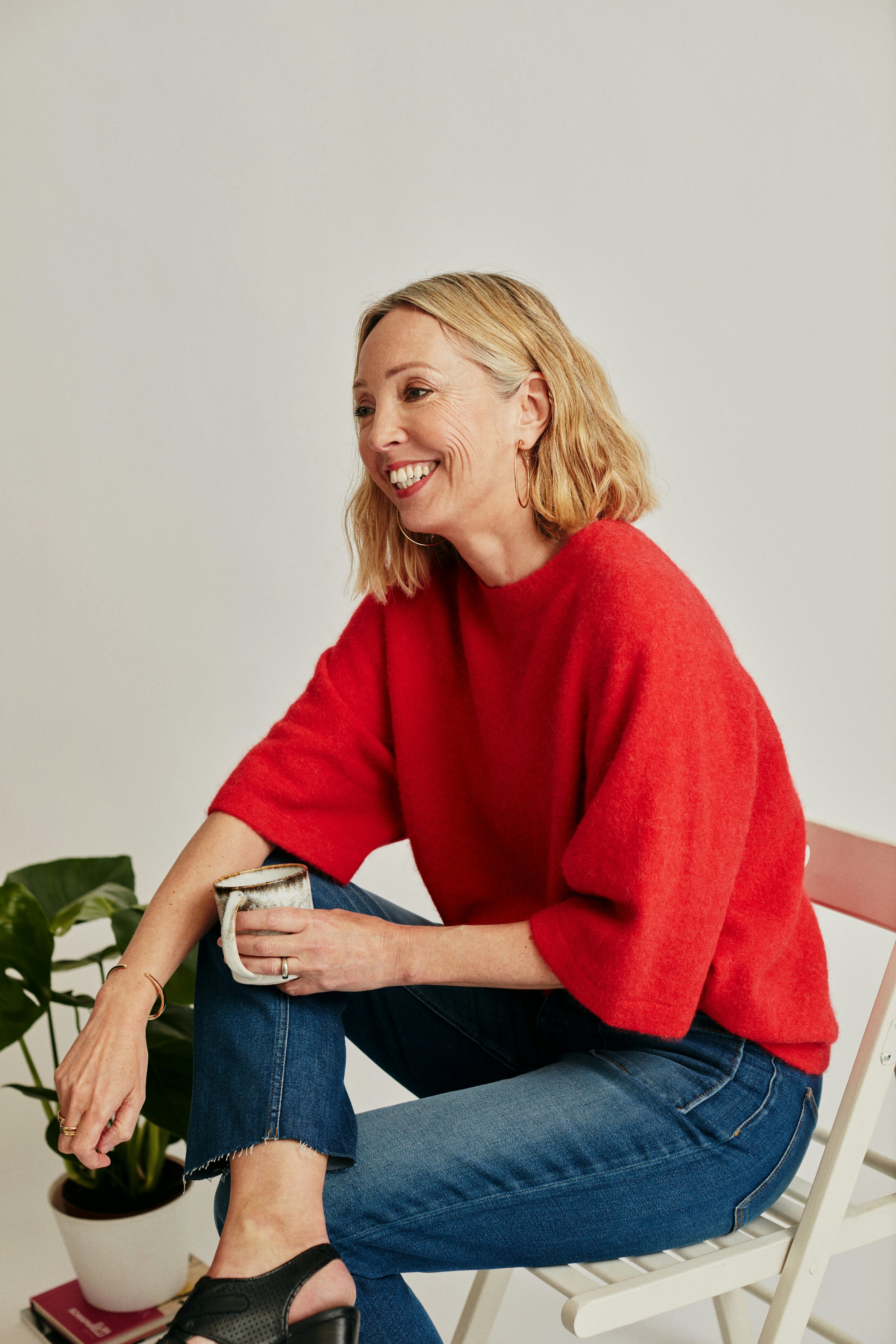 Middle aged woman wearing a red sweater, smiling, and drinking coffee. Arcadia Women’s Wellness Menopause and Hormone Therapy - Phoenix Arizona