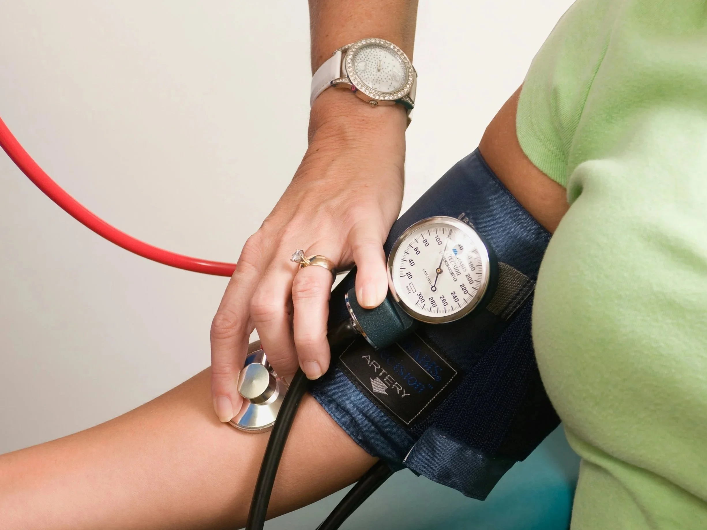 Woman nurse checking another woman's blood pressure.