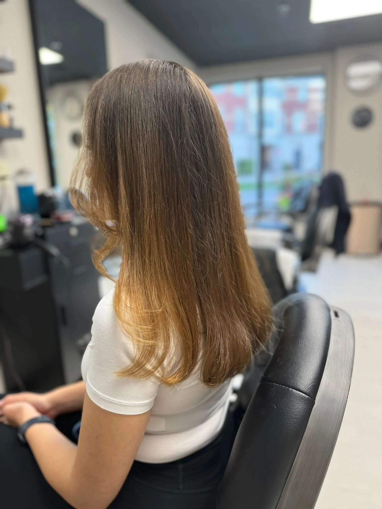 Person with long, wavy, brown hair sitting in a salon chair.
