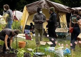   Marcus Henderson, center left, talks with Adam Powers at the gardens at the Capitol Hill Autonomous Zone (CHAZ) or the Capitol... (Erika Schultz / The Seattle Times)    More   