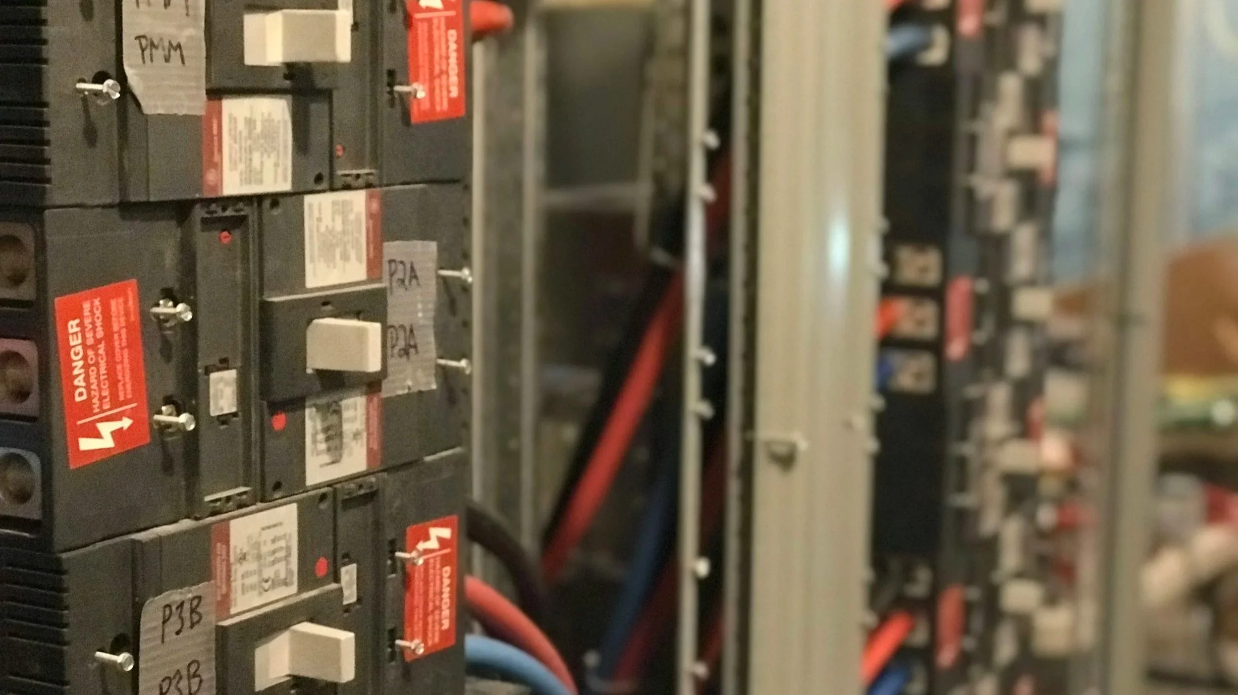 Close-up view of electronic circuit breakers with red and black wires connected, mounted on a panel.