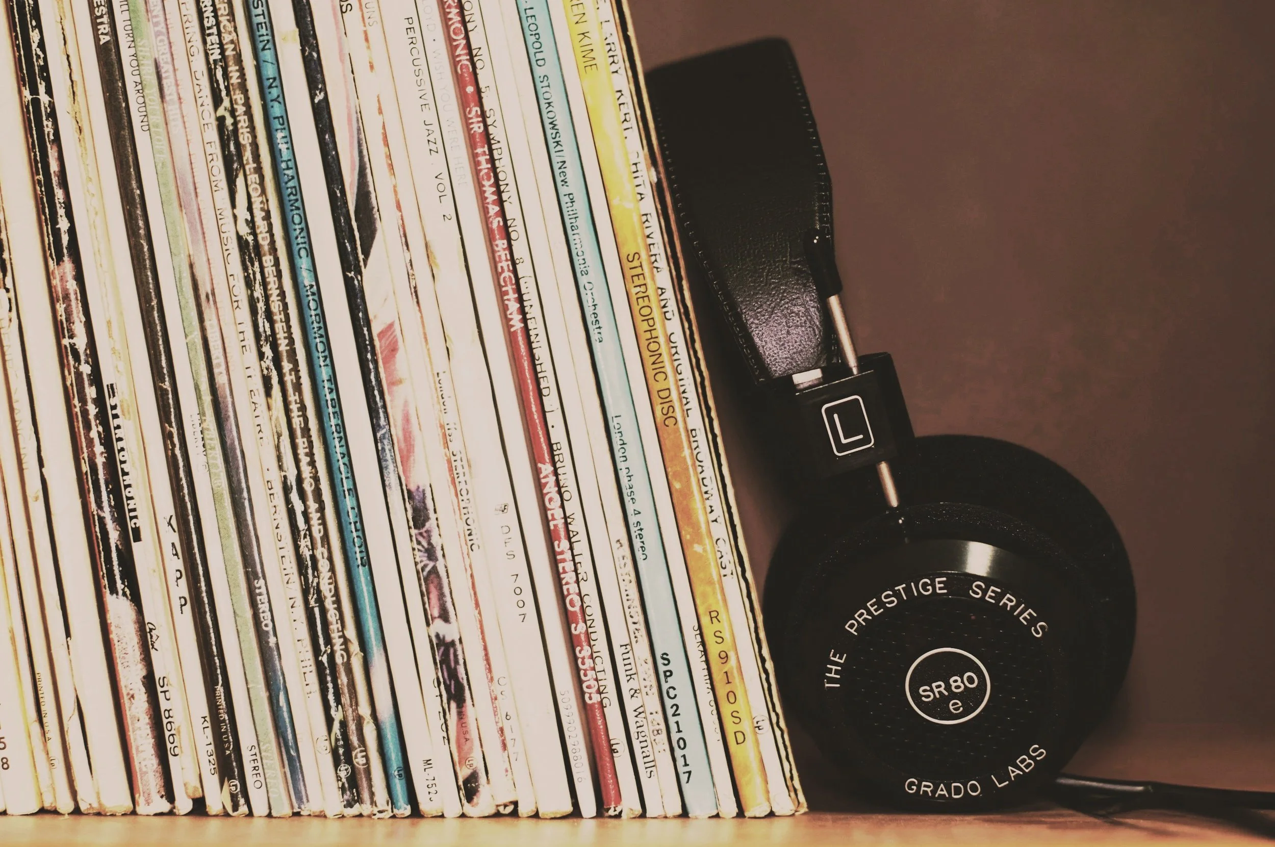 A collection of colorful books with their spines facing outward on a shelf, next to a black coffee mug with white text that reads 'The Prestige Series SR80'.