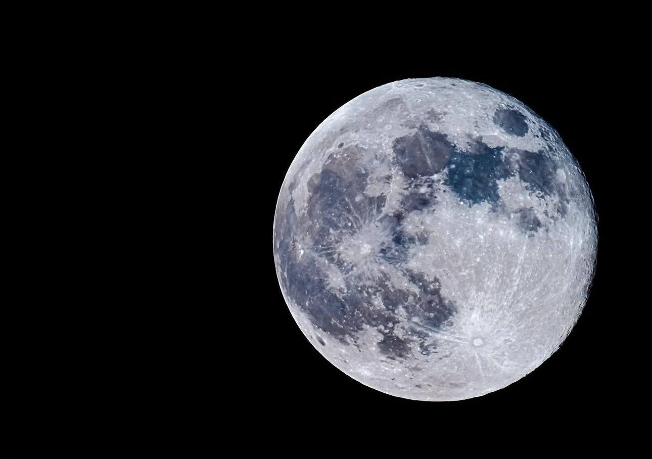 Close-up of the full moon against a black night sky showing detailed craters and surface features.
