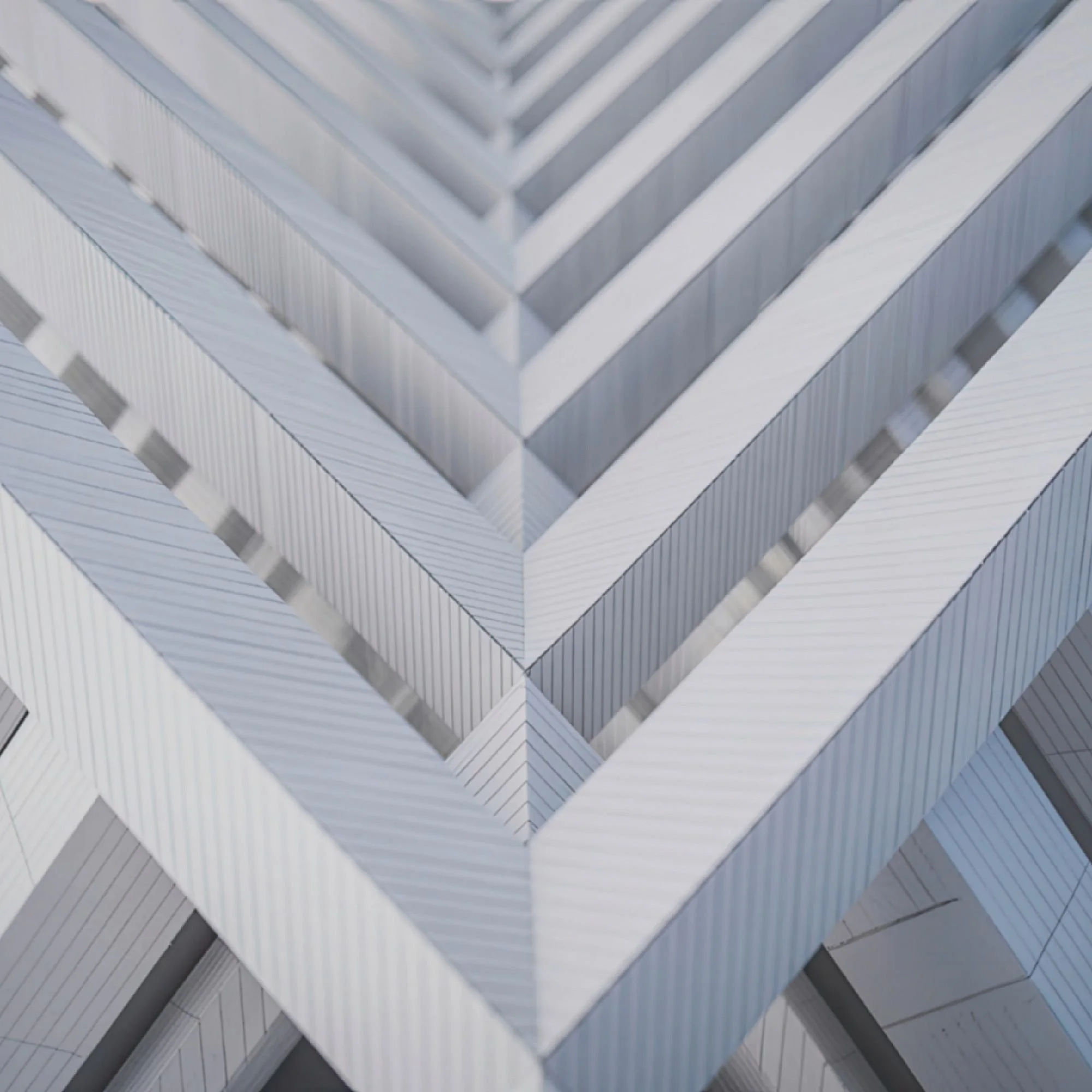 Close-up view of an abstract, modern architectural structure made of metallic panels with a pattern of alternating light and shadow.