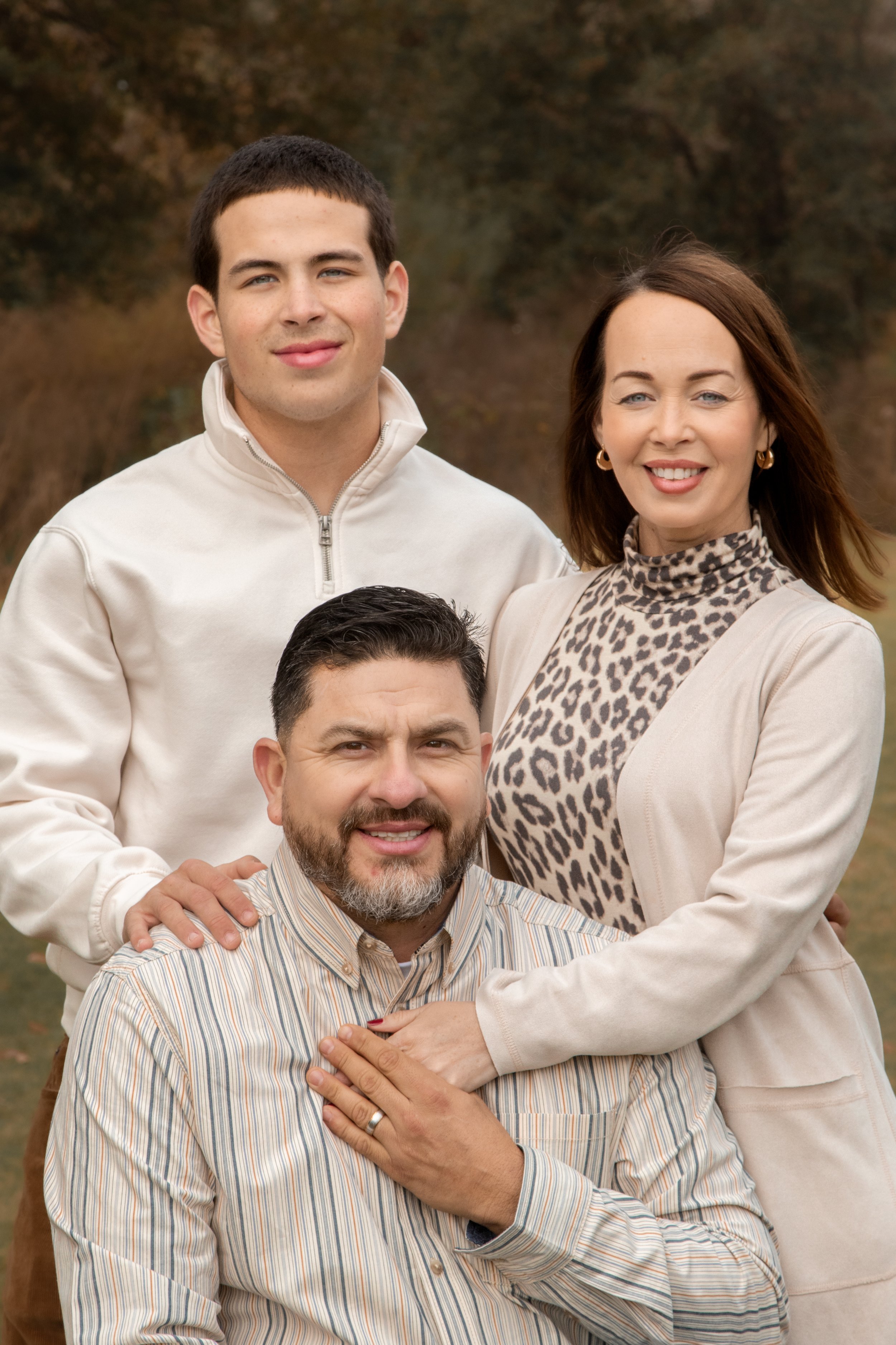 Group photo of five people outdoors in autumn, smiling, with a forest background.