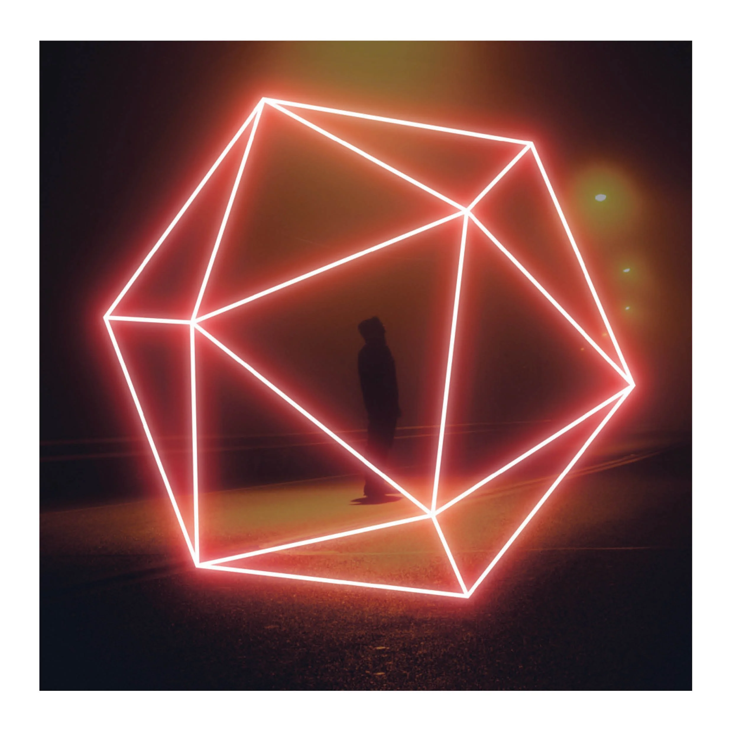 Nighttime scene of a geometric light installation shaped like a cube with white neon outlines, standing on a dark ground with silhouettes of people around it.