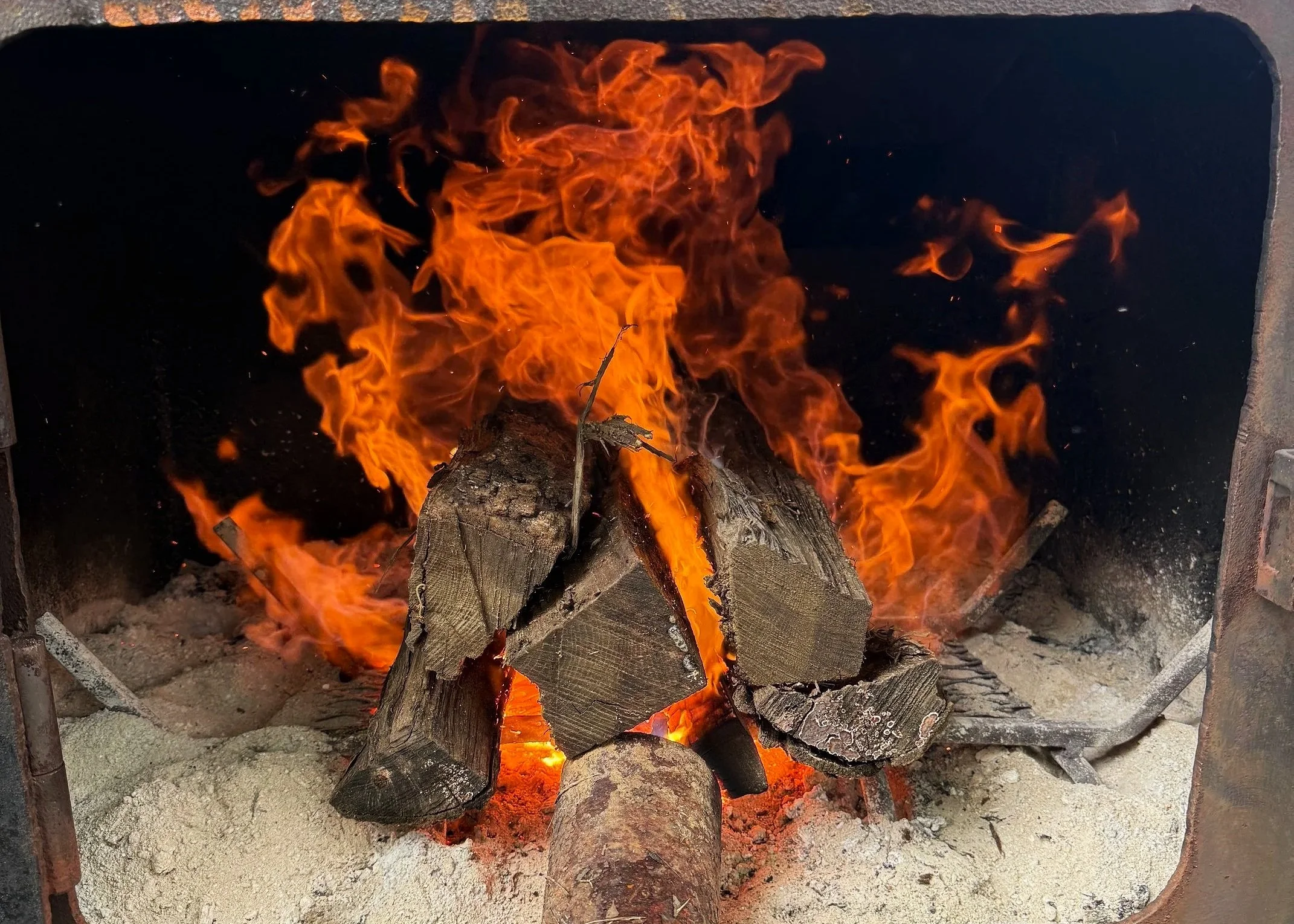 A wood fire burning in a fireplace with visible flames and logs.