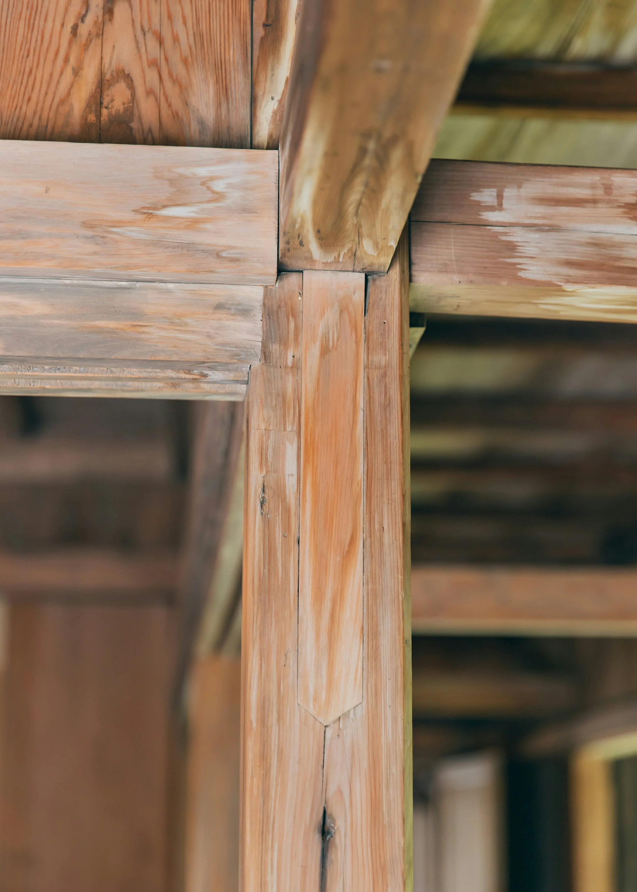 Close-up view of wooden planks, with some showing natural wood grain and knots, stacked horizontally in an outdoor or construction setting.