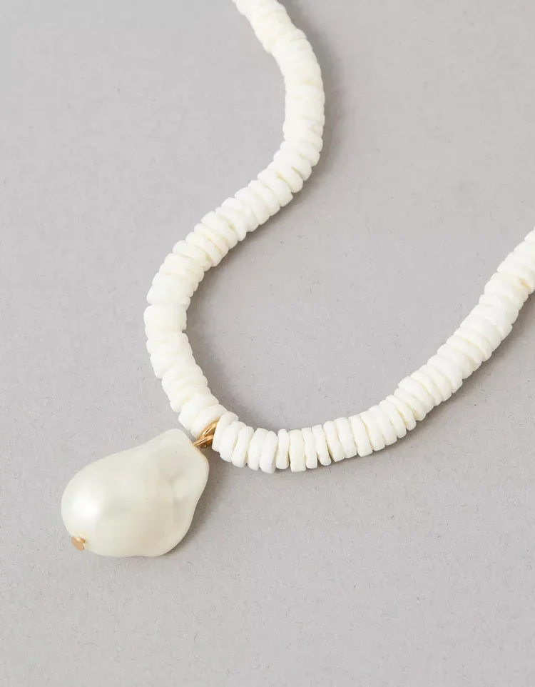 White beaded necklace with a large white pearl pendant on a gray background.