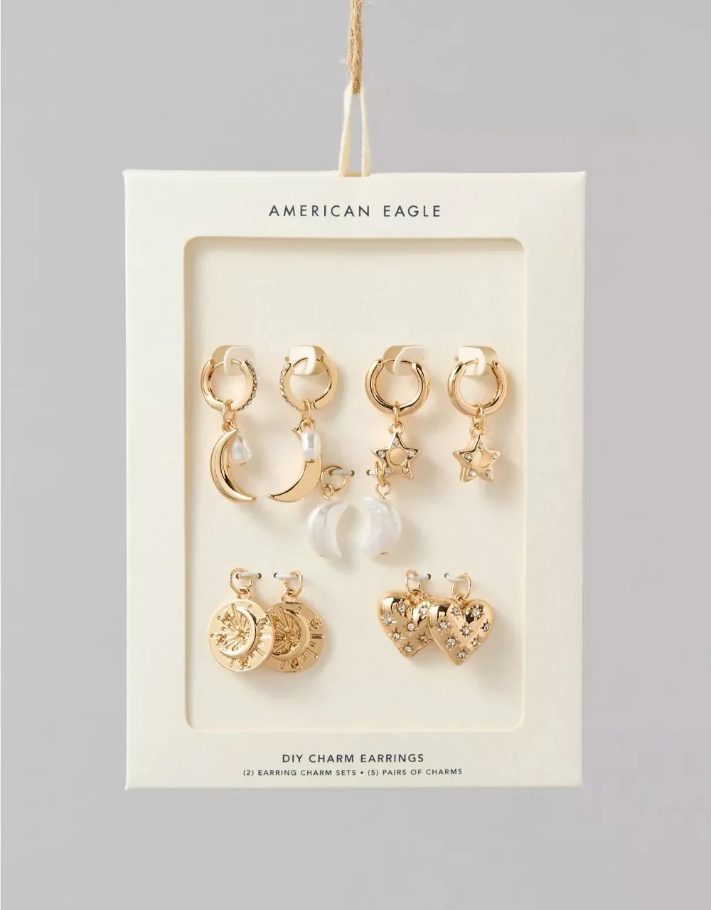 Set of five gold-tone charm earrings with celestial designs, including moons, stars, and hearts, displayed on white backing card by American Eagle.