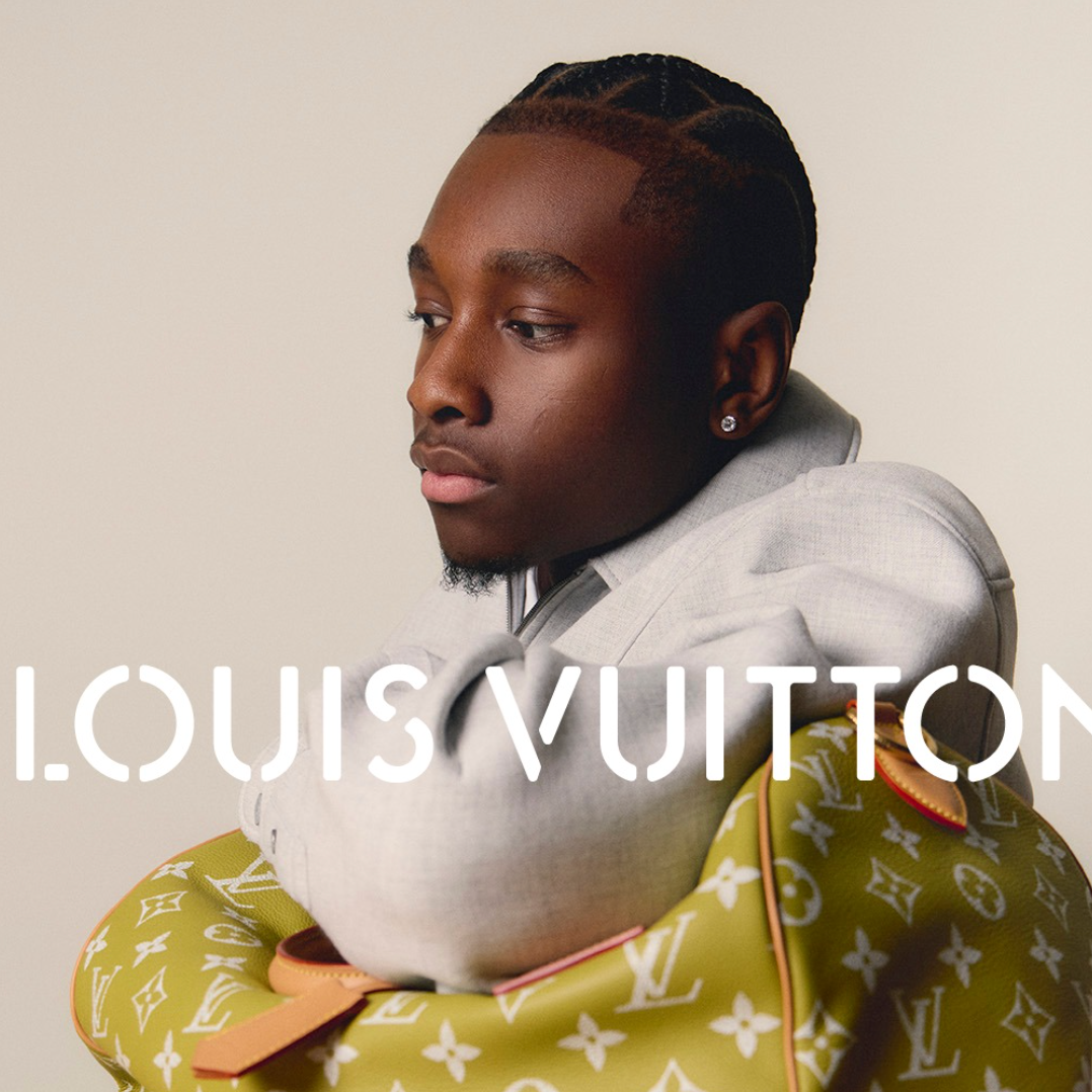 Young man with braided hair and earrings, wearing a light gray hoodie, holding a yellow Louis Vuitton bag with white monogram pattern and orange lining, with 'Louis Vuitton' logo overlayed.