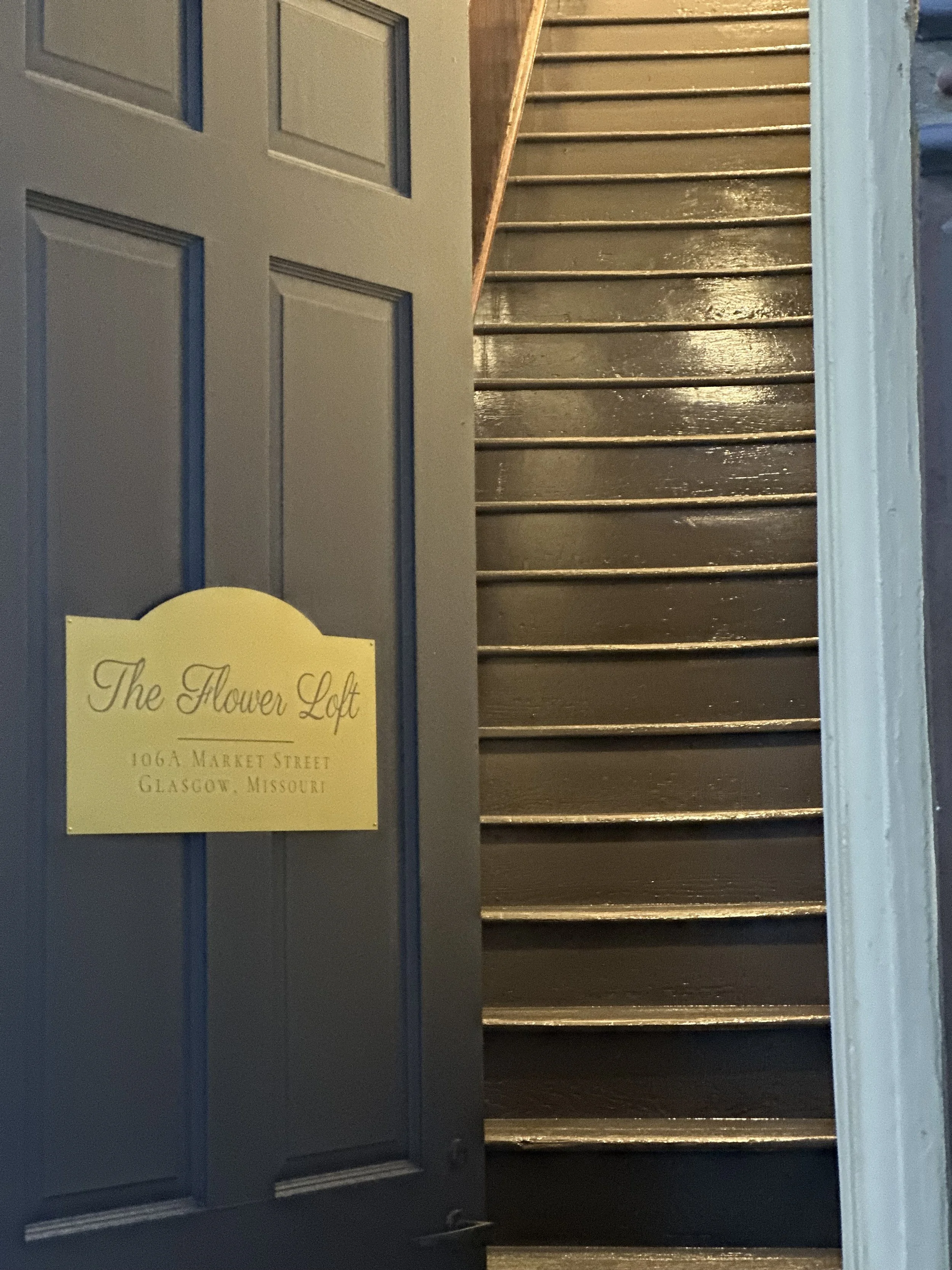 A partially open blue door revealing stairway with dark wooden steps.