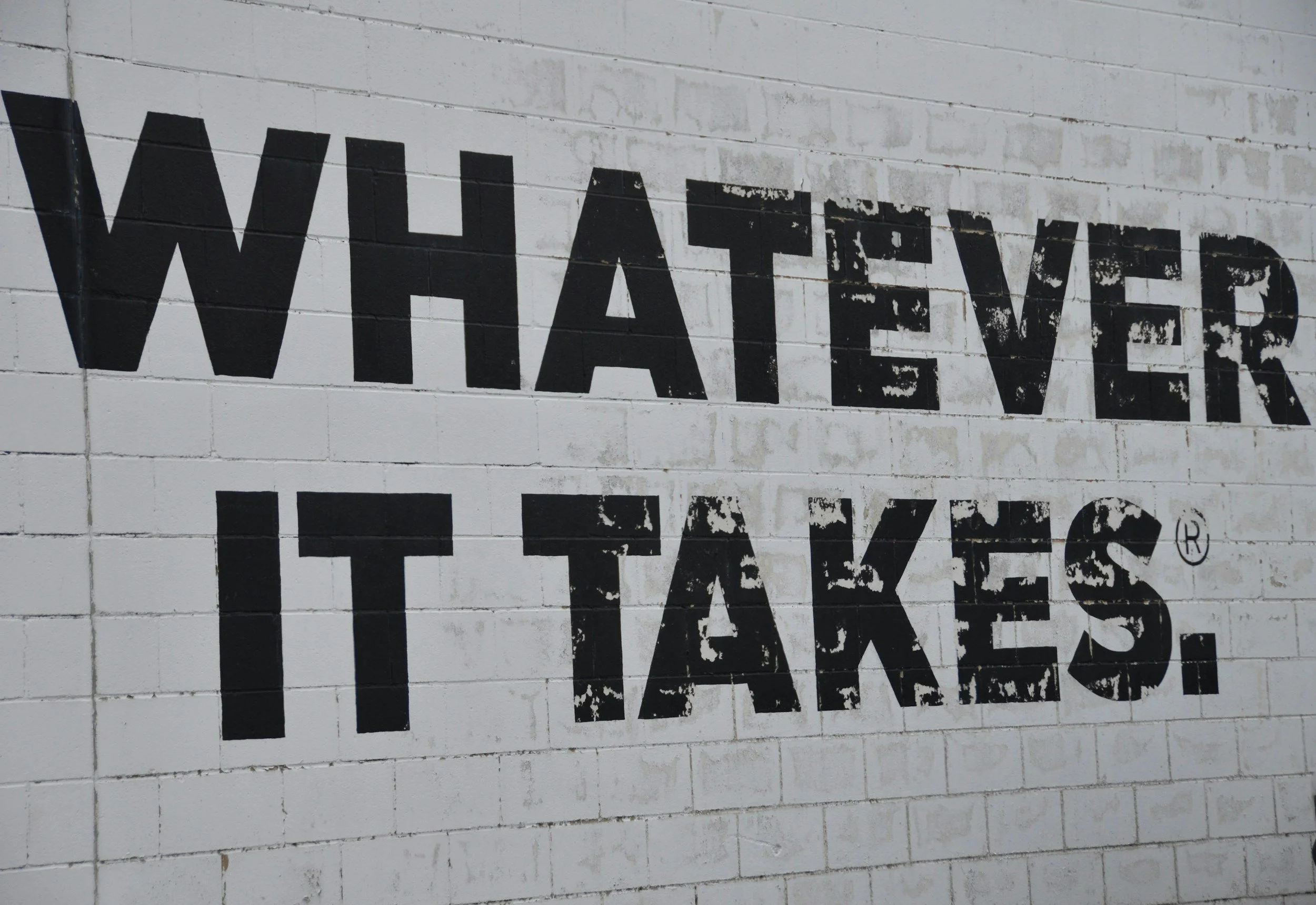 Close-up of a white brick wall with black spray-painted text reading 'WHALEAVER'.