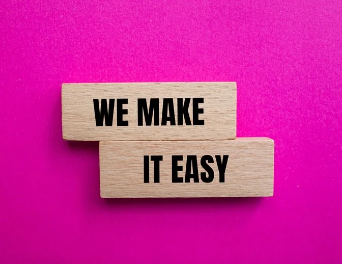 Wooden blocks with black text on a pink background saying, 'WE MAKE IT EASY.'