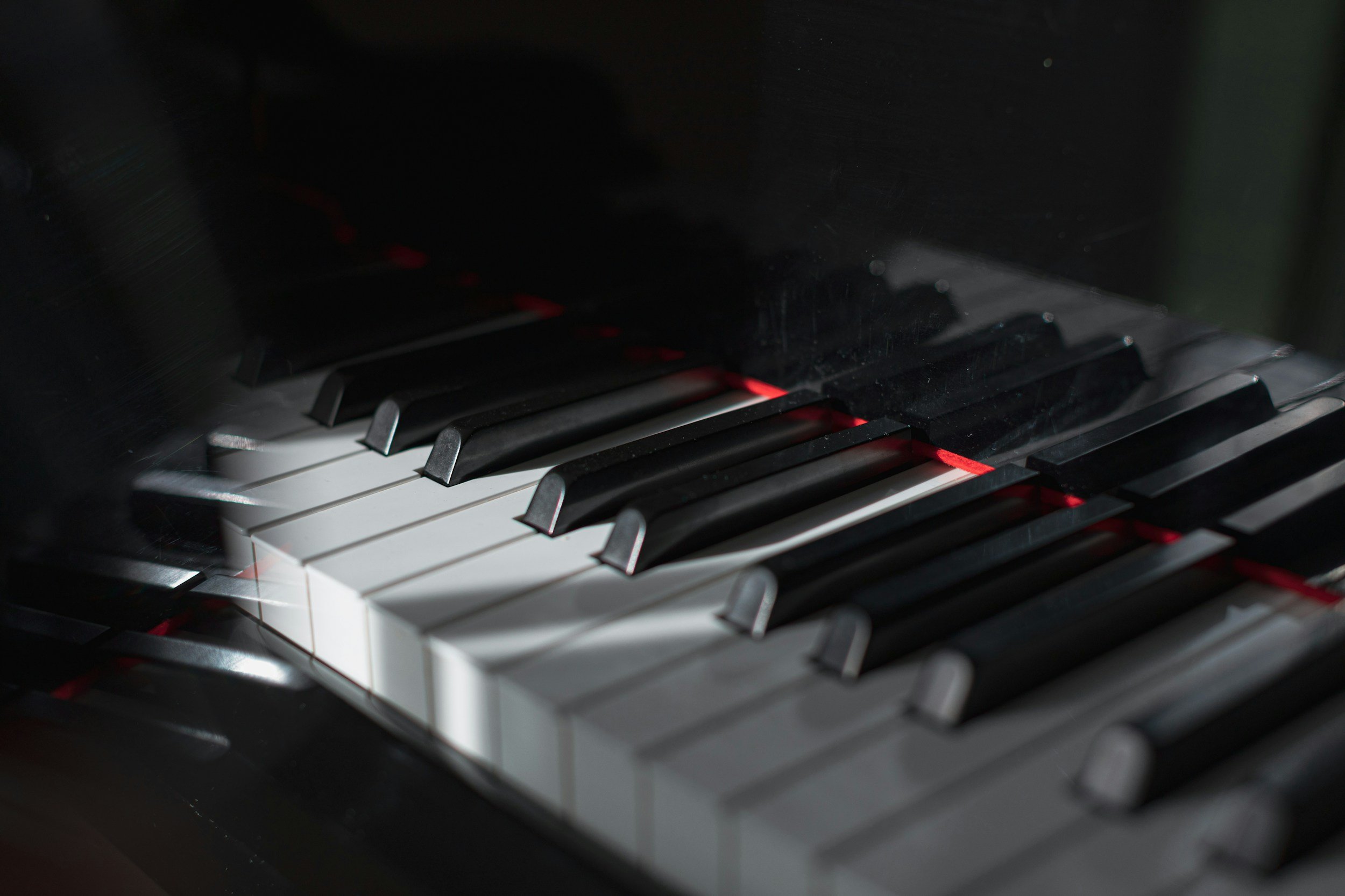 Close-up of piano keys with some black and white keys visible in a dimly-lit setting.