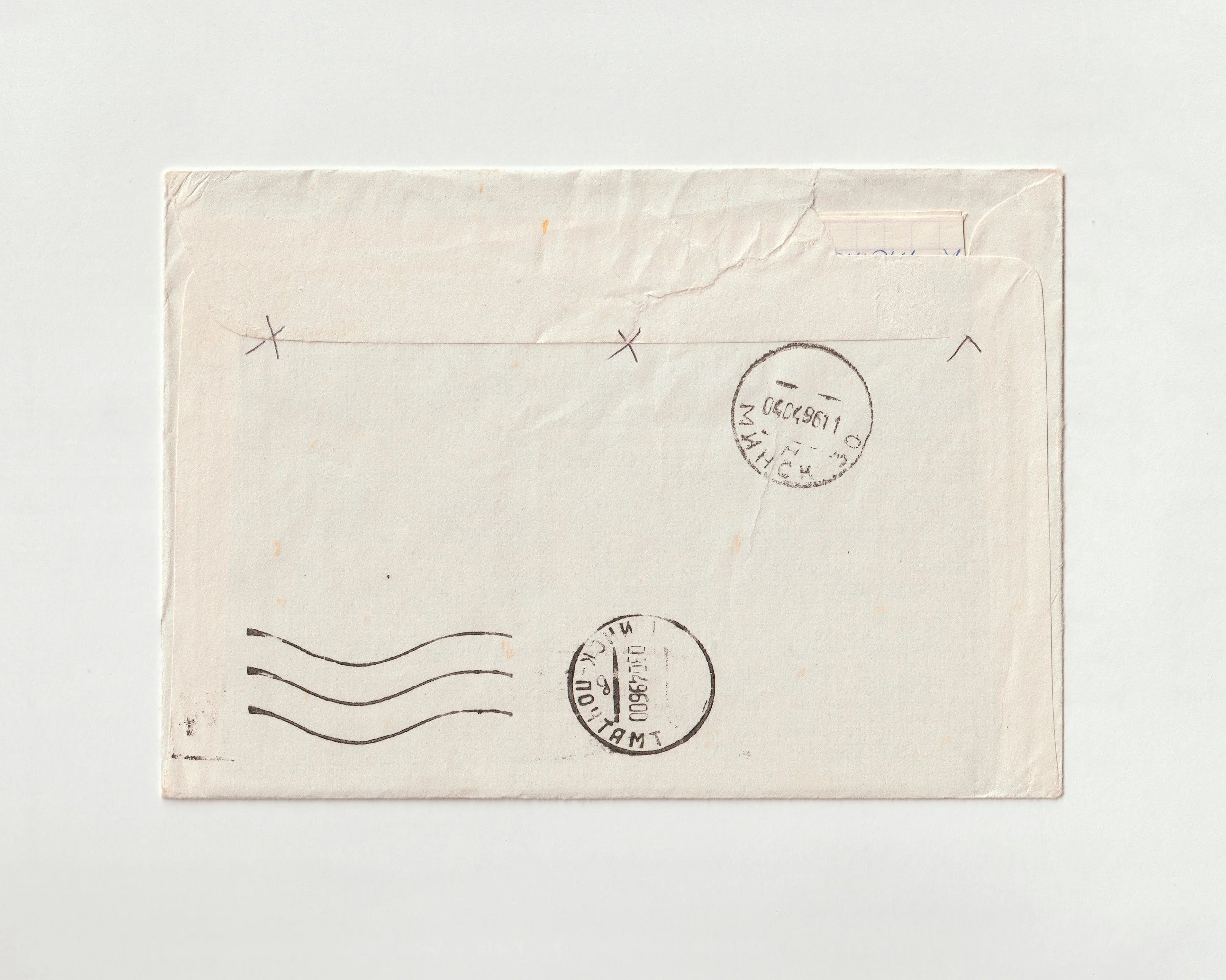 The image shows the back of an envelope with postal stamps and markings, placed on a white background.