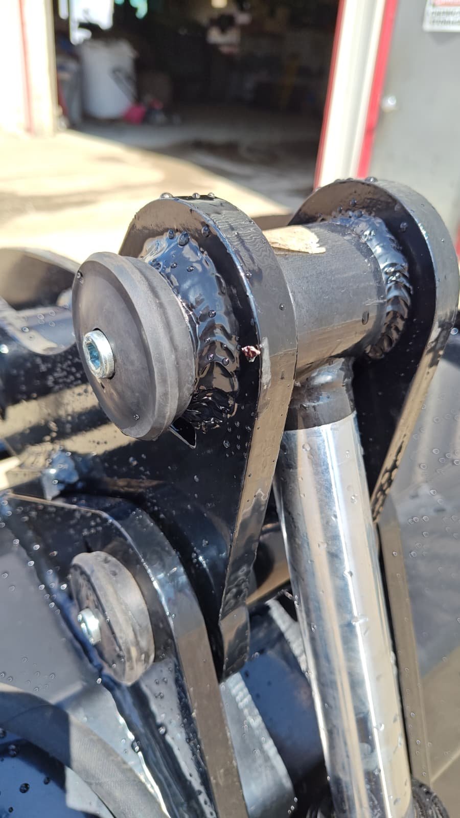 Close-up of a skateboard truck with wet grease and oil on it, mounted on the skateboard deck.