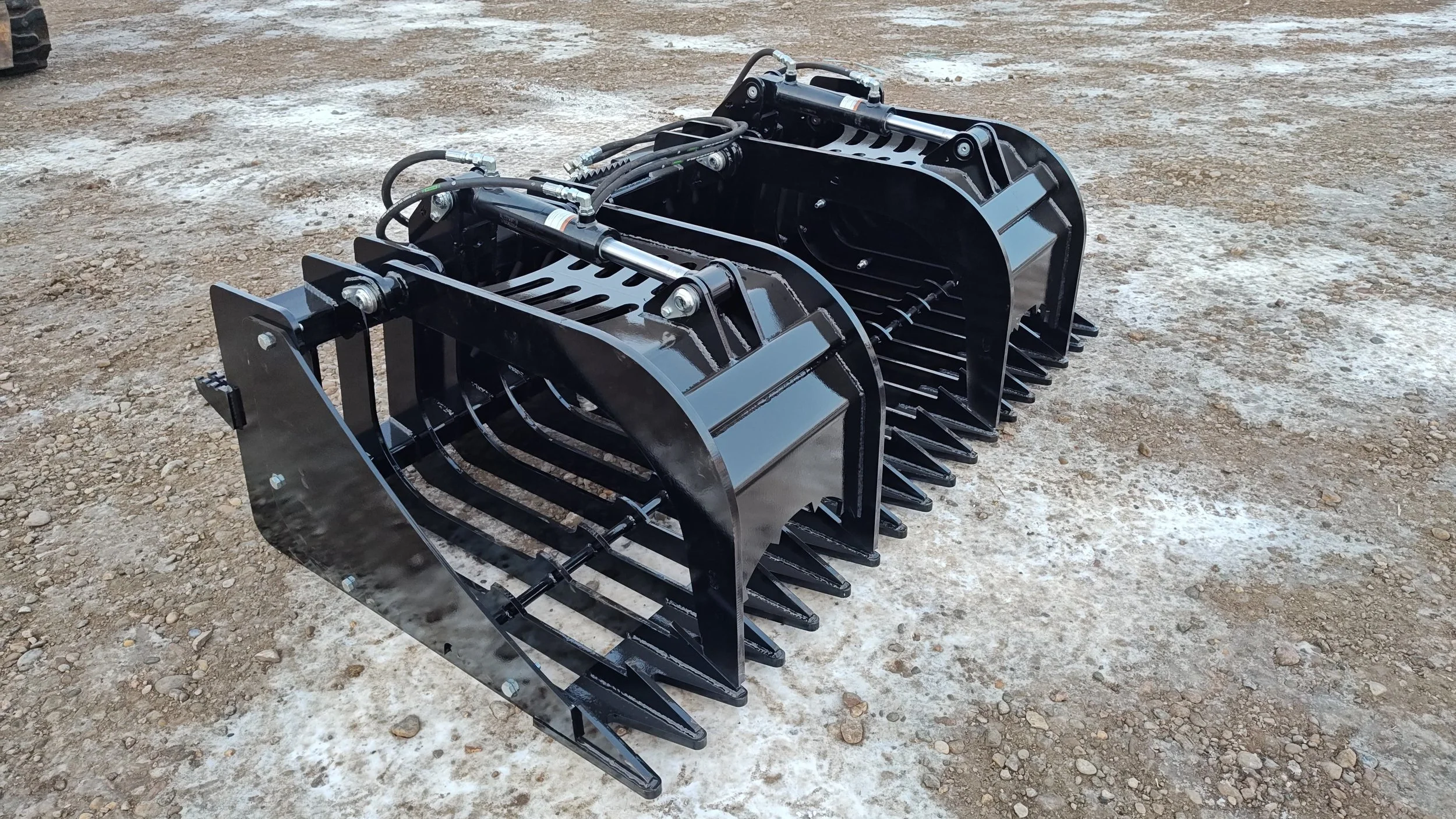 Black hydraulic attachment for heavy machinery on dirt ground.
