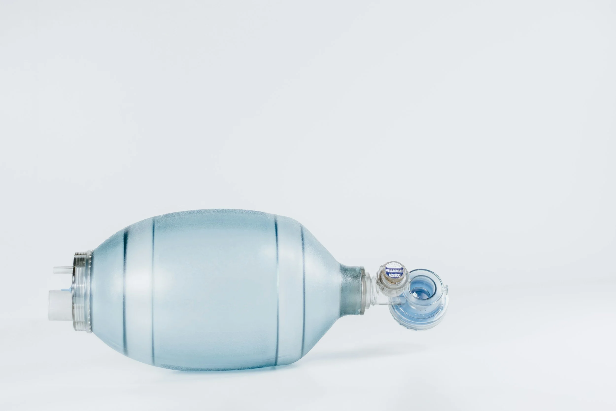 A metallic oxygen tank with a pressure gauge and valve, placed on a white surface against a plain white background.