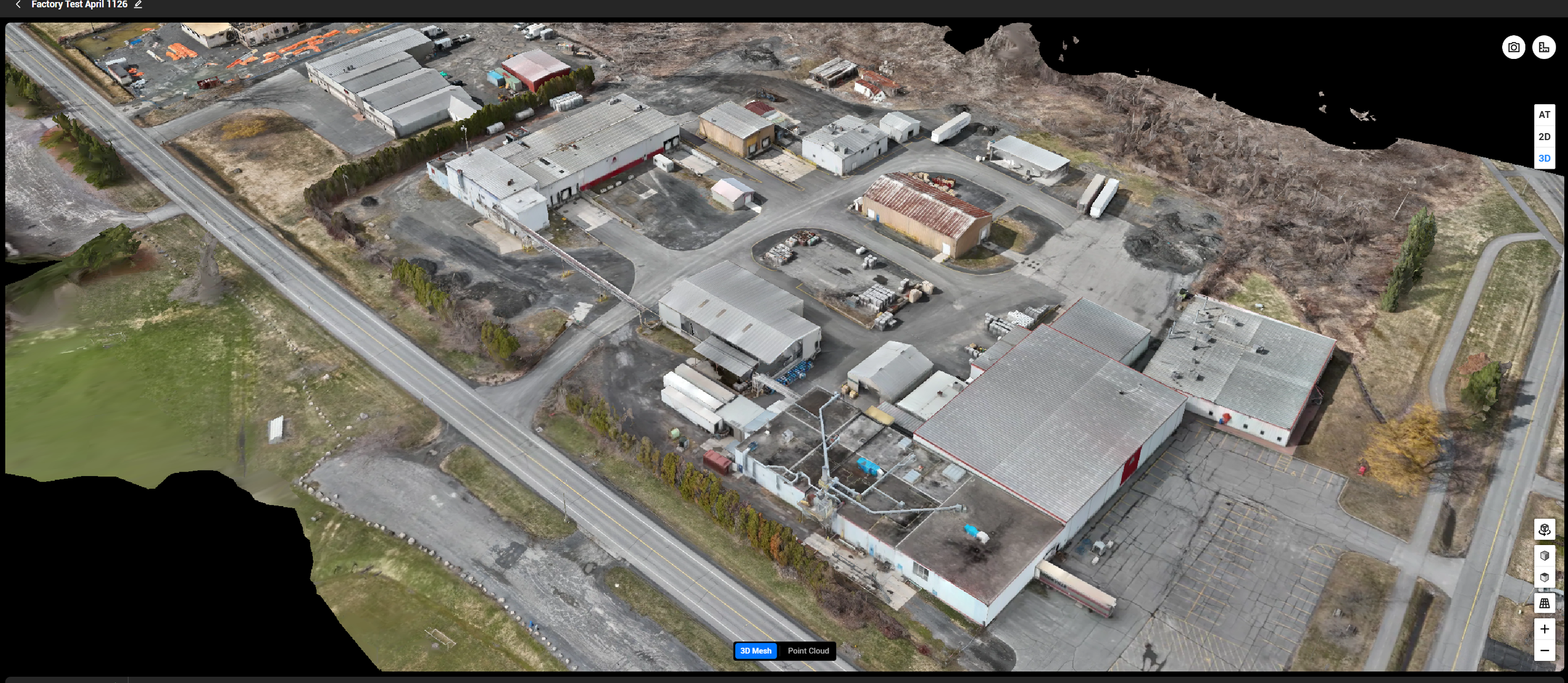 Generated 3d model view of an industrial complex with multiple buildings, parking lots, and surrounding roads, with some trees and open land nearby collected using drone photogrammetry.