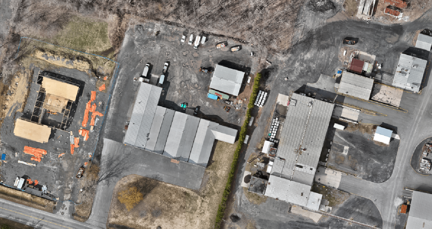 Aerial view of a construction site and industrial area with buildings, parking lots, vehicles, and construction materials created using orthomosaic drone capture.