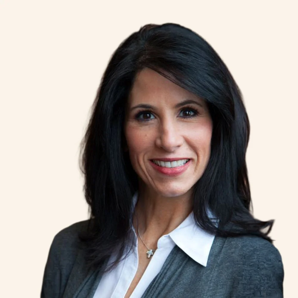 Headshot of a woman with black hair, smiling, wearing a white blouse and a gray cardigan.