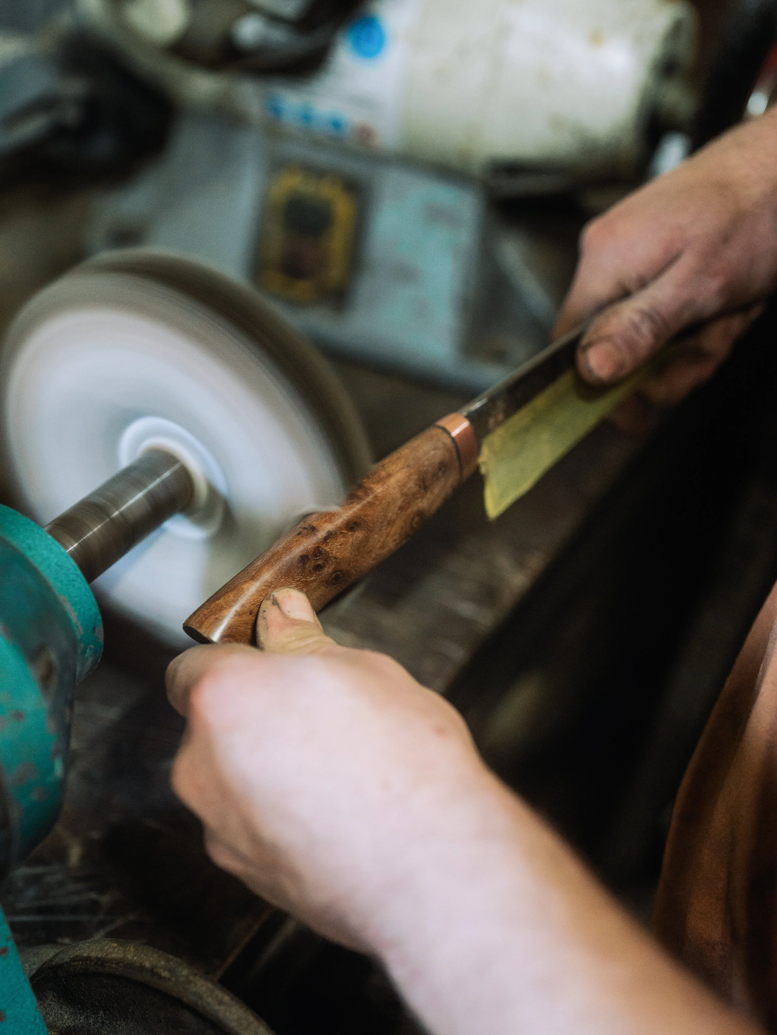 Person using a rotary tool to polish or grind a metal pipe in a workshop.