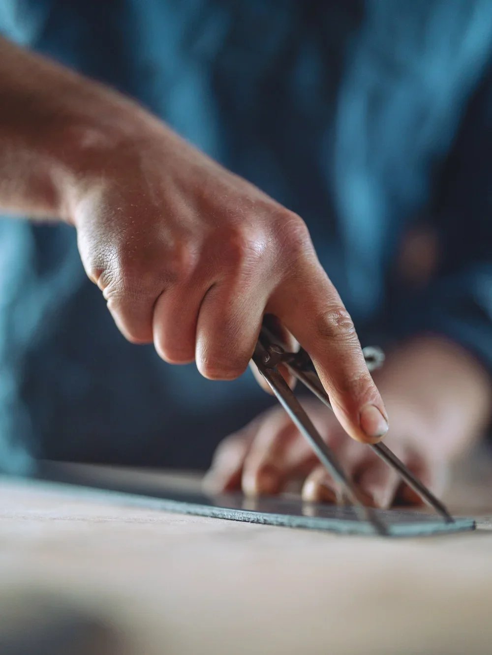 Close-up of a person's hand using scissors to cut paper on a table.