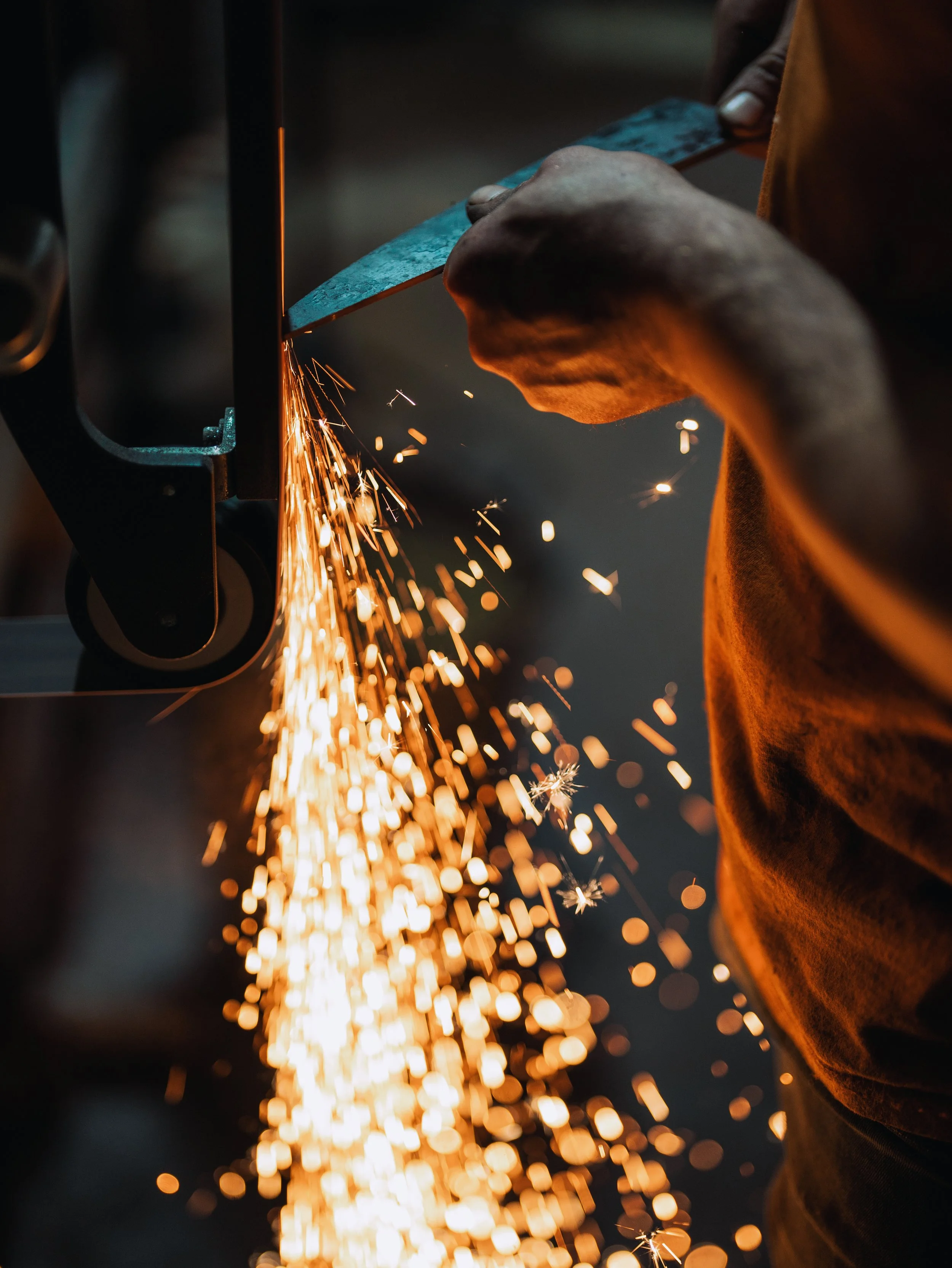 A person welding metal, with bright sparks flying in the air.