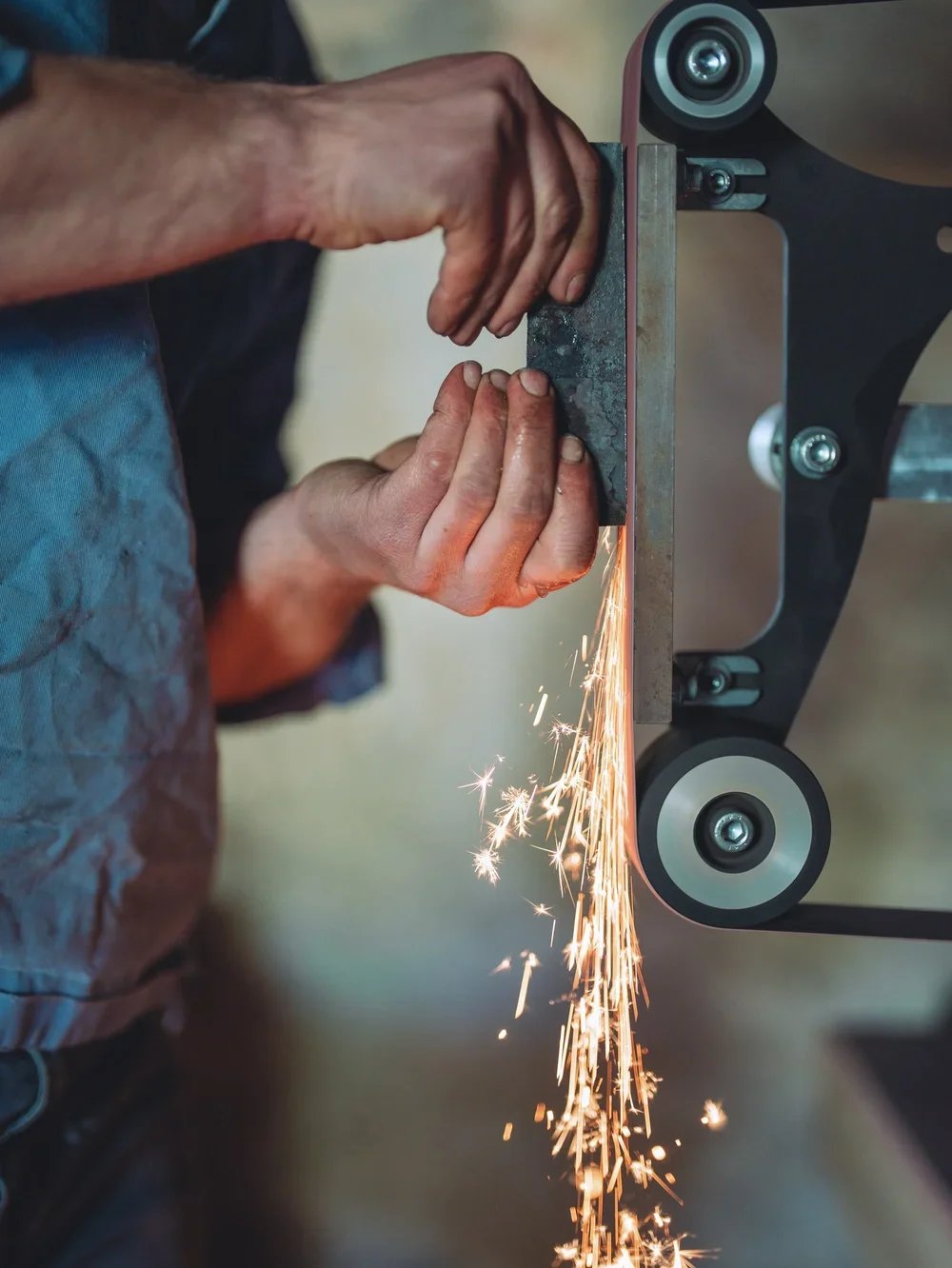 A person cutting metal using an angle grinder, with sparks flying.