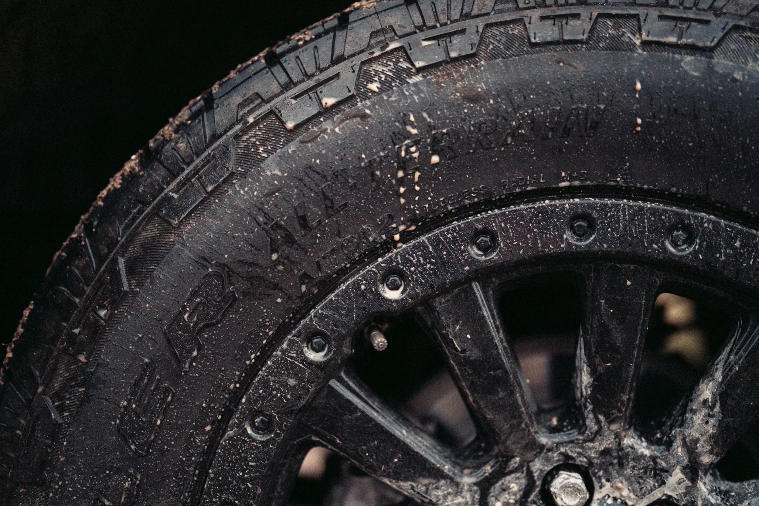 Close-up of two black tires stacked on top of each other with water droplets and some dirt on the surface.