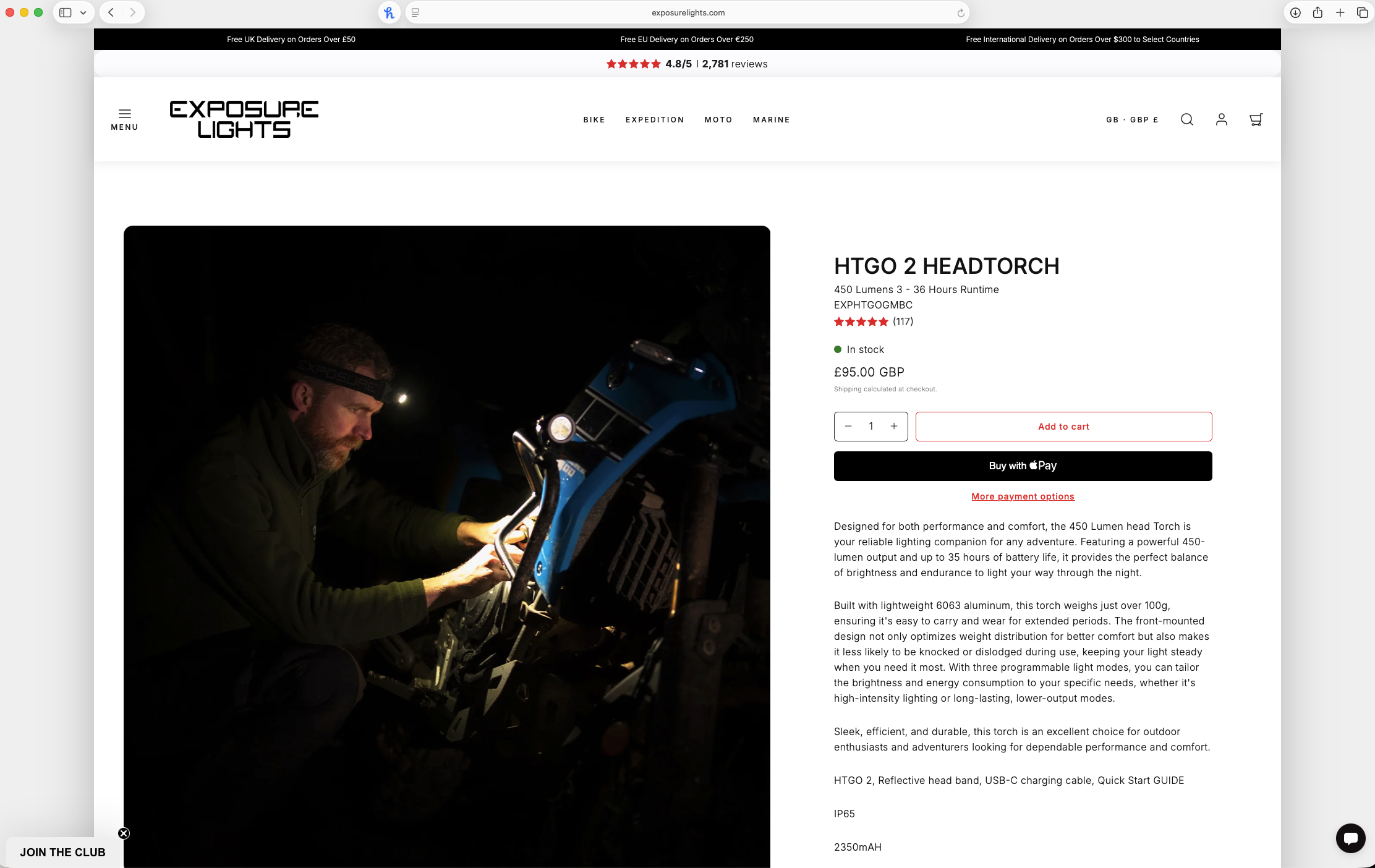 A man wearing a headlamp is working on a blue motorcycle at night, with the scene illuminated by the headlamp.