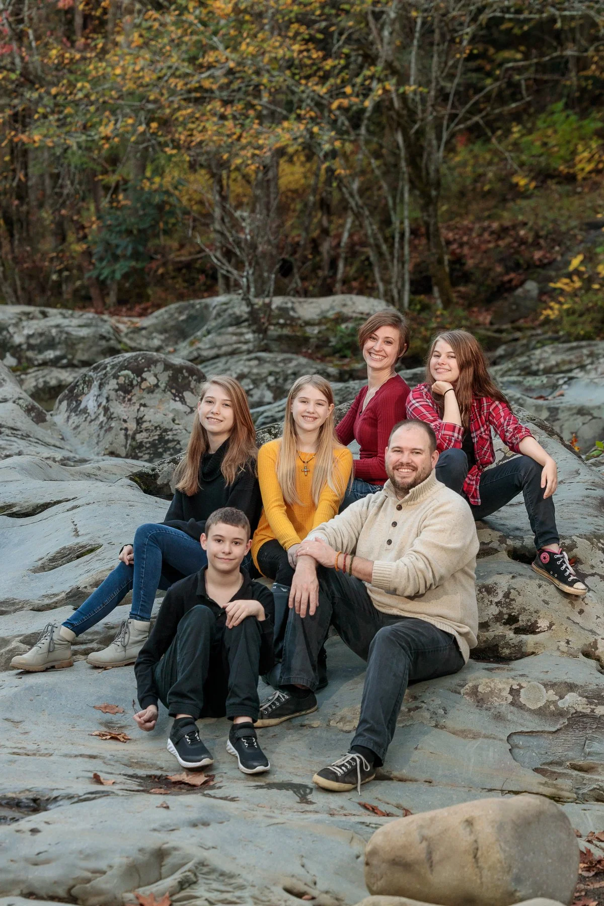 A family oposing on rocks among fall foliage in the Great Smoky Mountains National Park