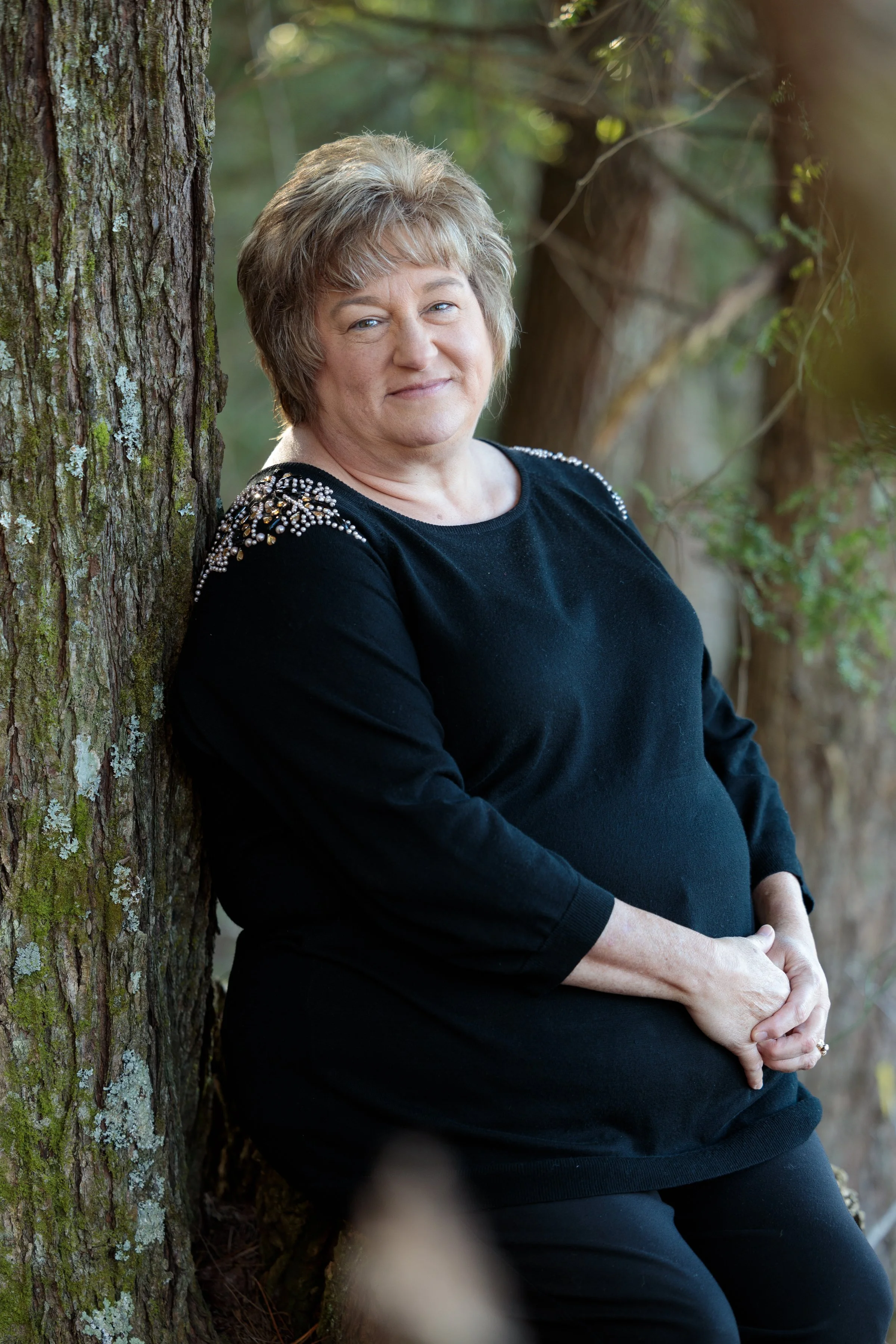 Portrait of a grandmother leaning against a mossy tree during a family photography session in Cades Cove.